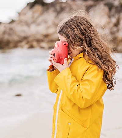 Side view of a young girl photographing on the beach.