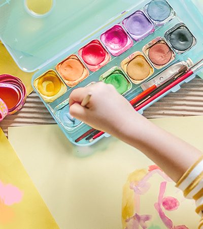 A girl playing with water colours inside room